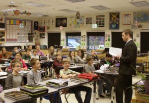 A high school teacher in front of a class of students in a science class